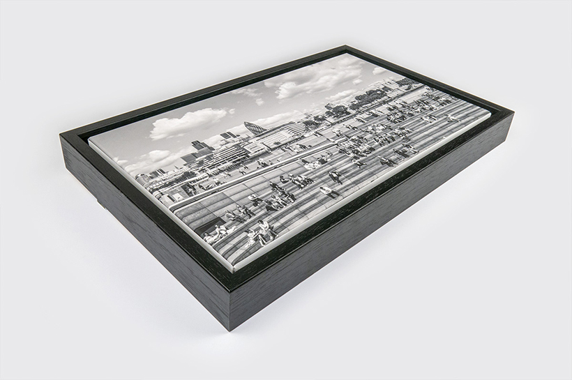 A framed black and white photograph of people sitting on steps in an urban setting, with city buildings in the background, echoes the timeless allure of art prints.