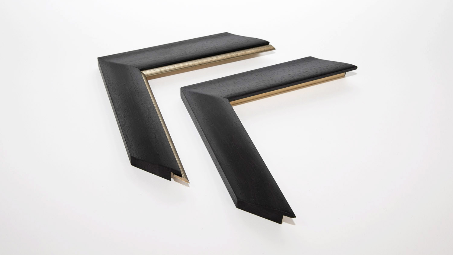 Two black mitered frame corners sit against a white background, showcasing their angled joints and layered edges, reminiscent of the precise craftsmanship seen in a framed football shirt.