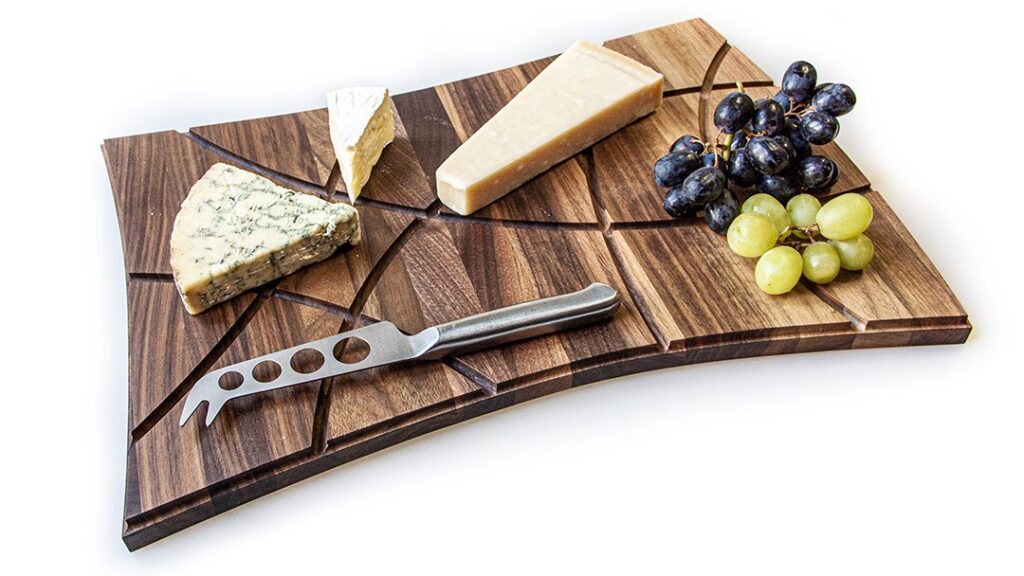 Upcycled wood chopping board with three cheeses and grapes on it