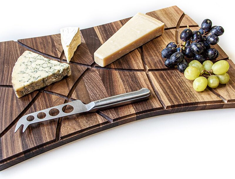 Upcycled wood chopping board with three cheeses and grapes on it