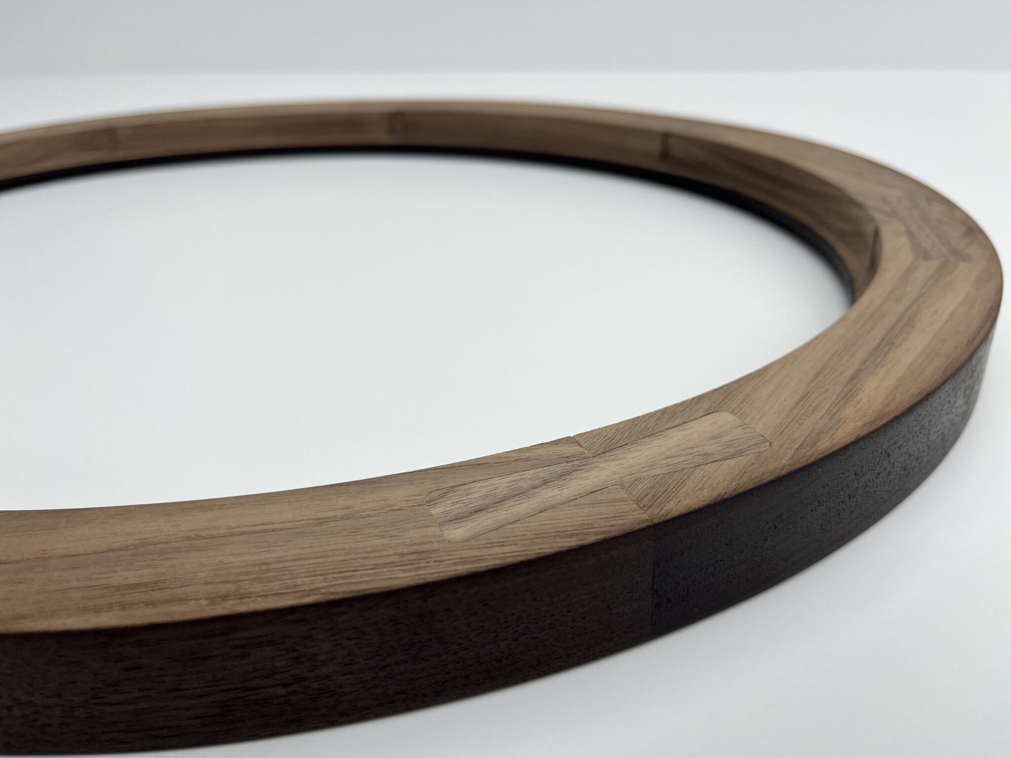 Close-up of a round wooden frame showcasing precise frame joints on a white background.