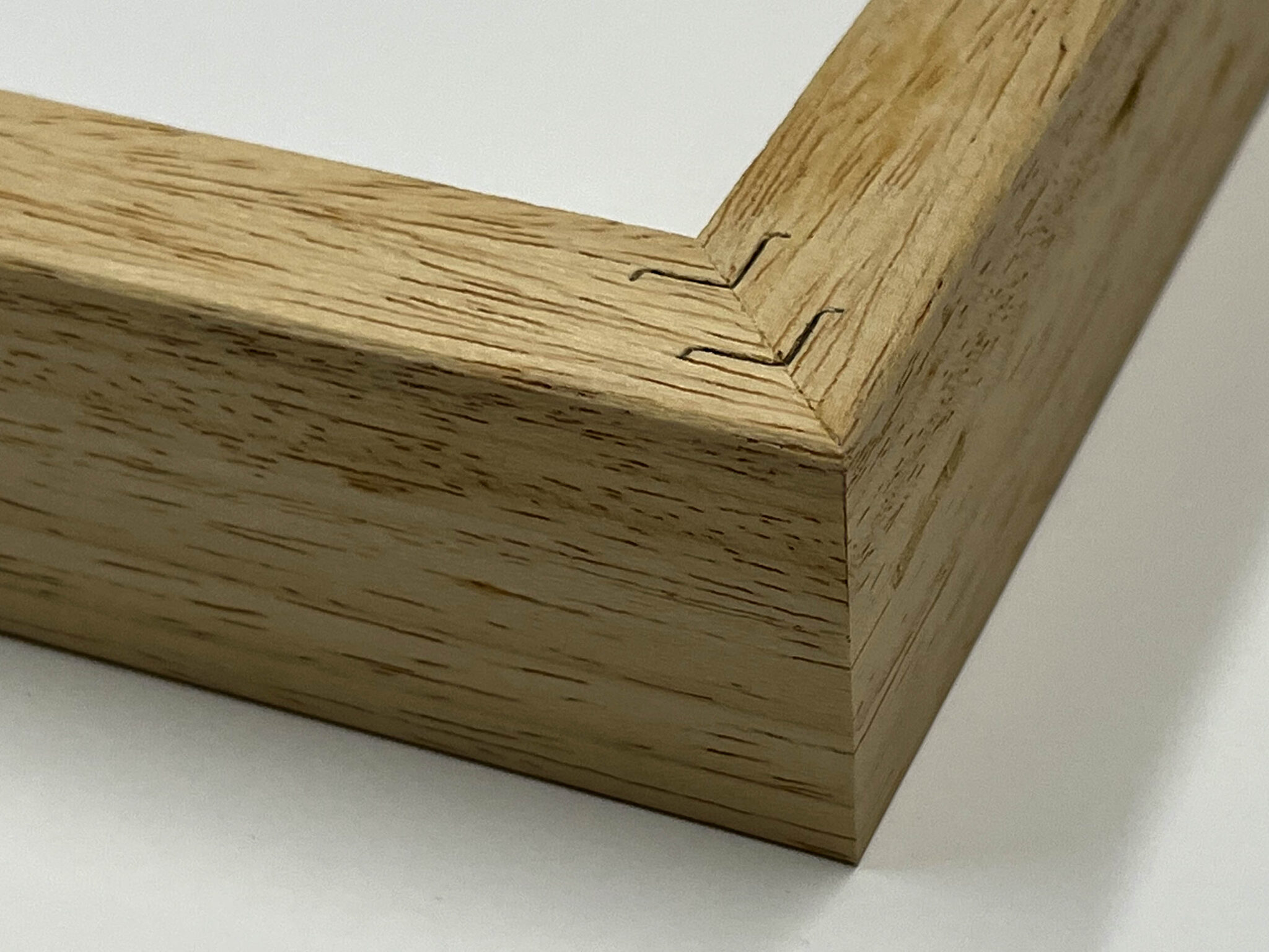 Close-up of a light wood picture frame corner with visible frame joints on a white background.