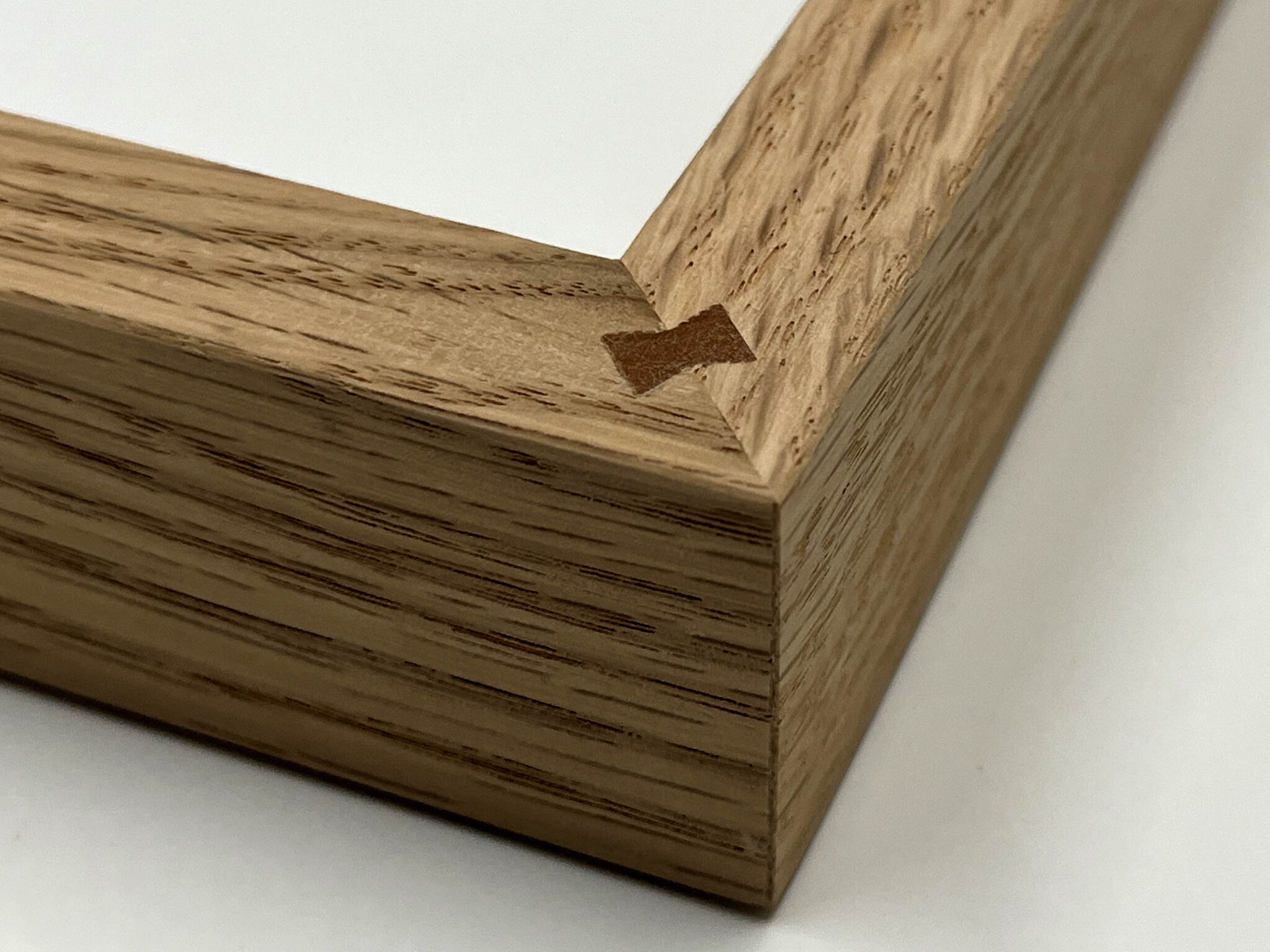 Close-up of a wooden picture frame corner showcasing frame joints with a visible bowtie joint.