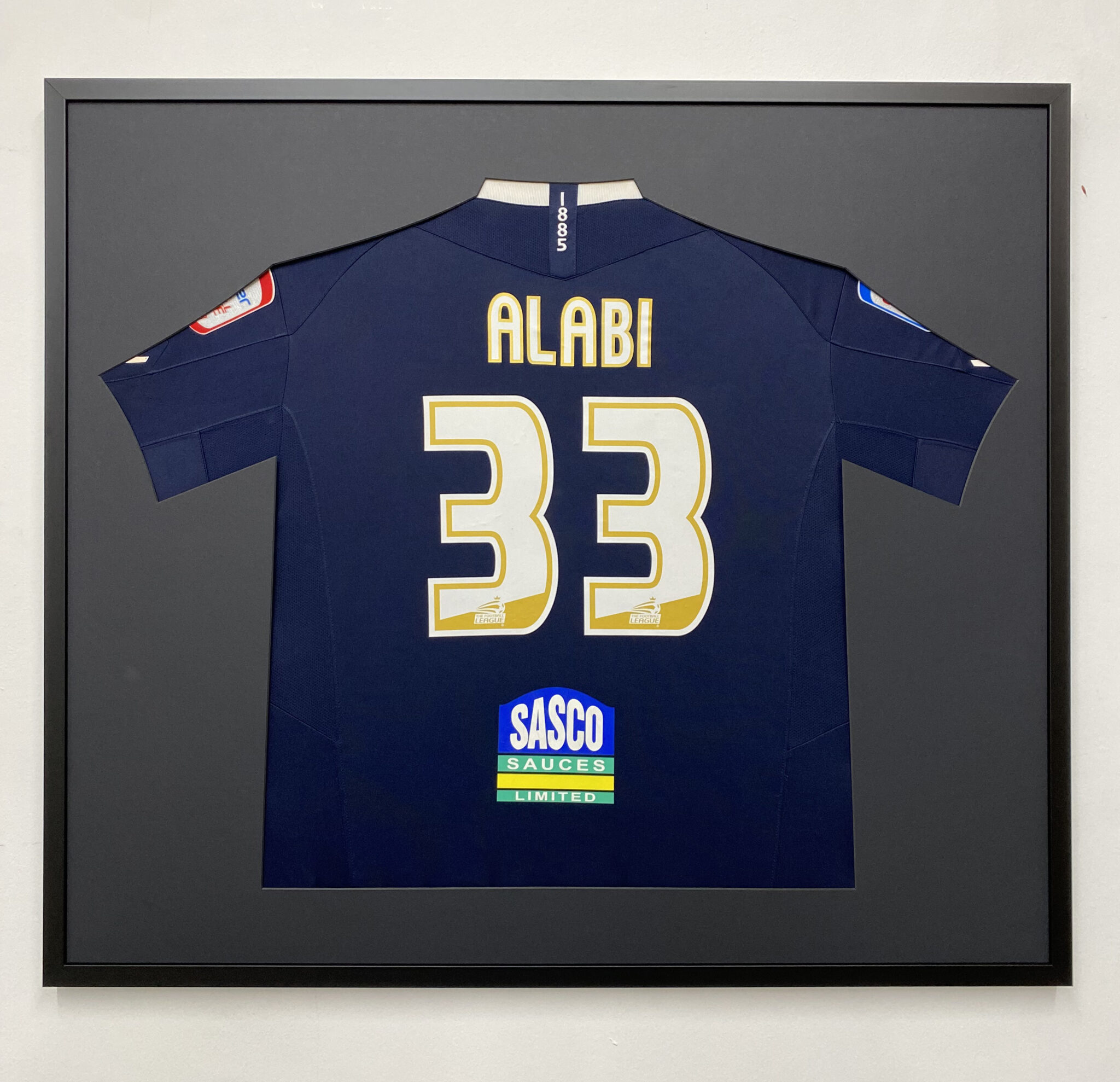 Framed navy football jersey with the name "Alabi" and number 33, displayed in a football shirt frame