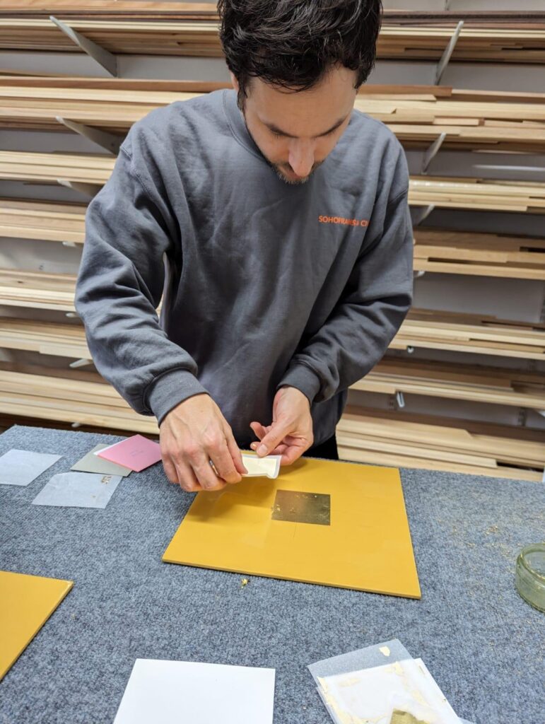 A person applies gold leaf to a frame during the gilded frames workshop
