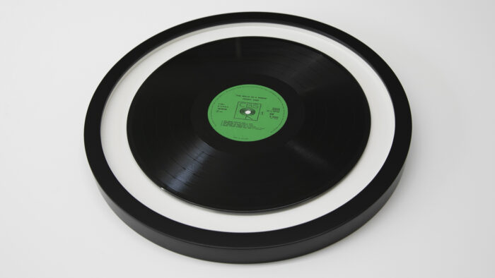 A black vinyl record is Vinyl Record Framing mounted in a round frame on a white background.