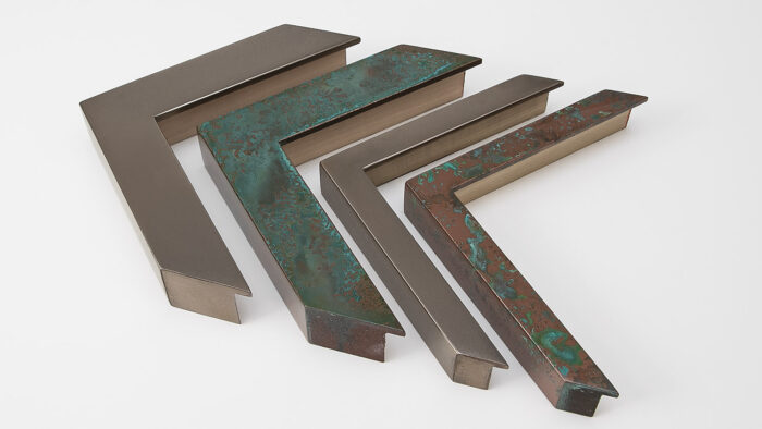 Four liquid copper metal frame corners with varying patinas arranged on a white background.