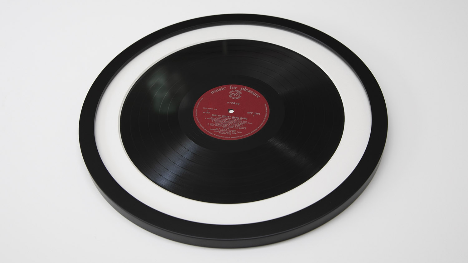 Vinyl Record Framing: A red-label record is showcased in a round black frame on a white background.