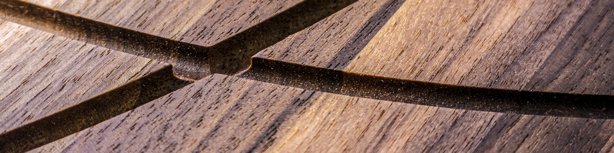 Close-up of intersecting dark lines on a wooden chopping board with visible grain and texture.