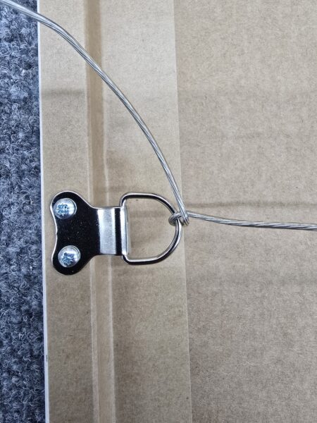 Close-up of a picture frame back showing a metal D-ring hanger with attached hanging wire.