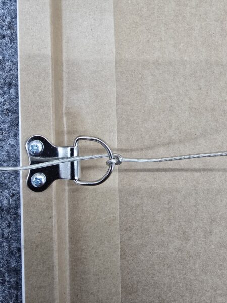 Close-up of a metal picture hanging wire attached to a D-ring on the back of a frame.