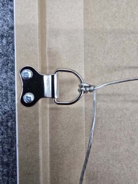 Close-up of a picture frame’s metal D-ring hanger and wire attached to the wooden frame.