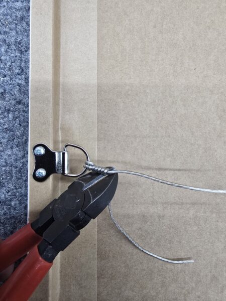 Wire cutters trim hanging wire attached to a bracket on the back of a framed picture or artwork.