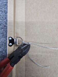 Wire cutters trim hanging wire attached to a bracket on the back of a framed picture or artwork.