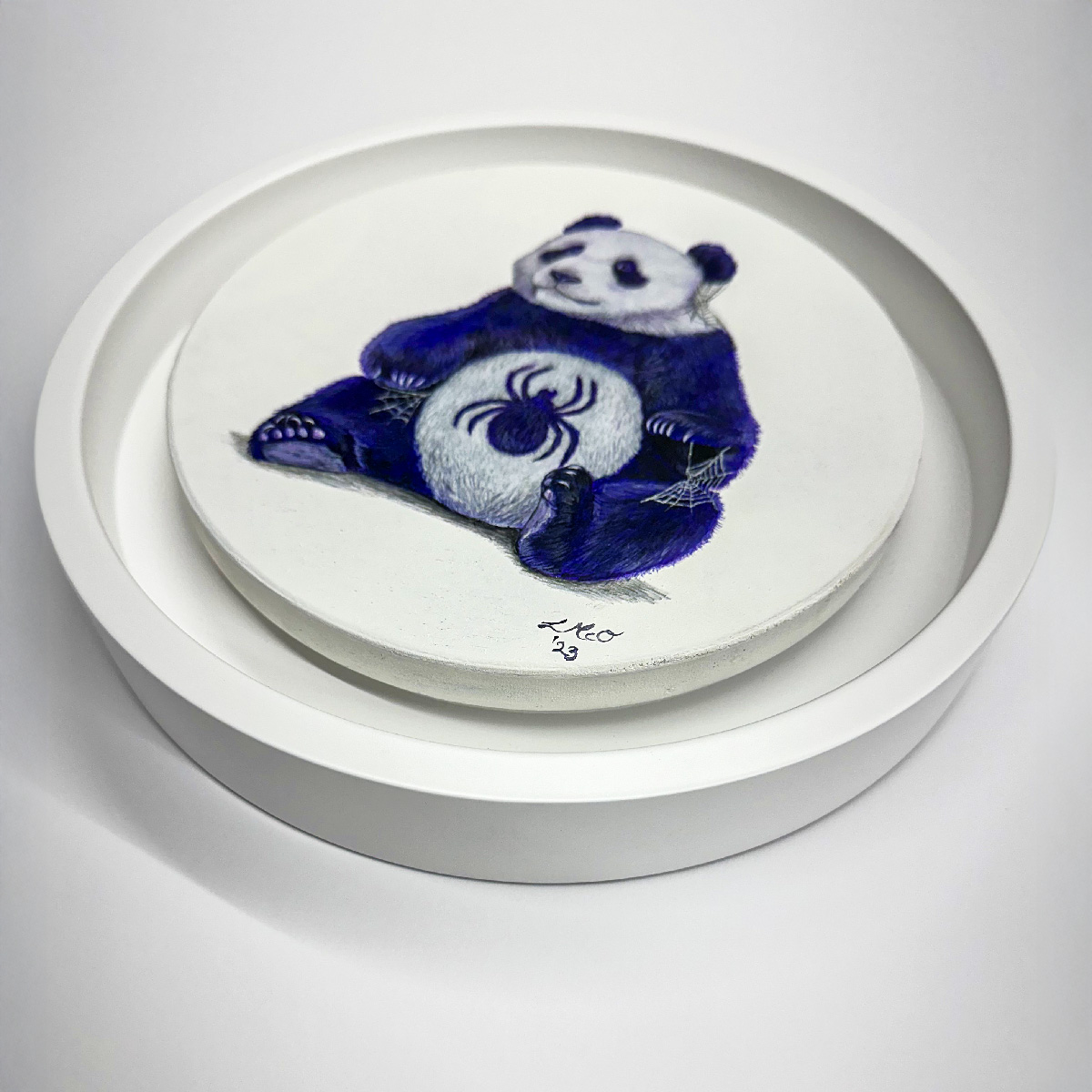 A circular artwork shows a relaxed purple panda with a black spider on its belly, in a white frame.