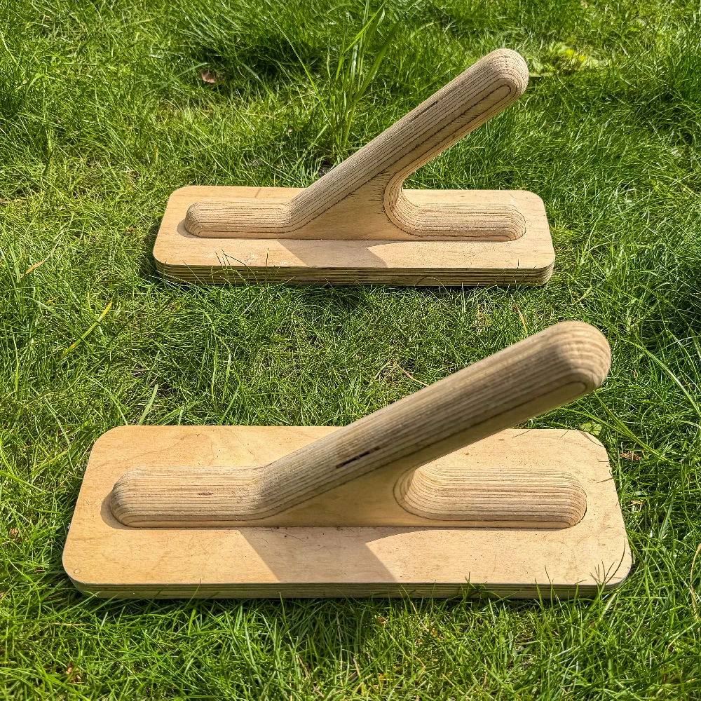 Close up of two wooden planche parallettes on a grass lawn
