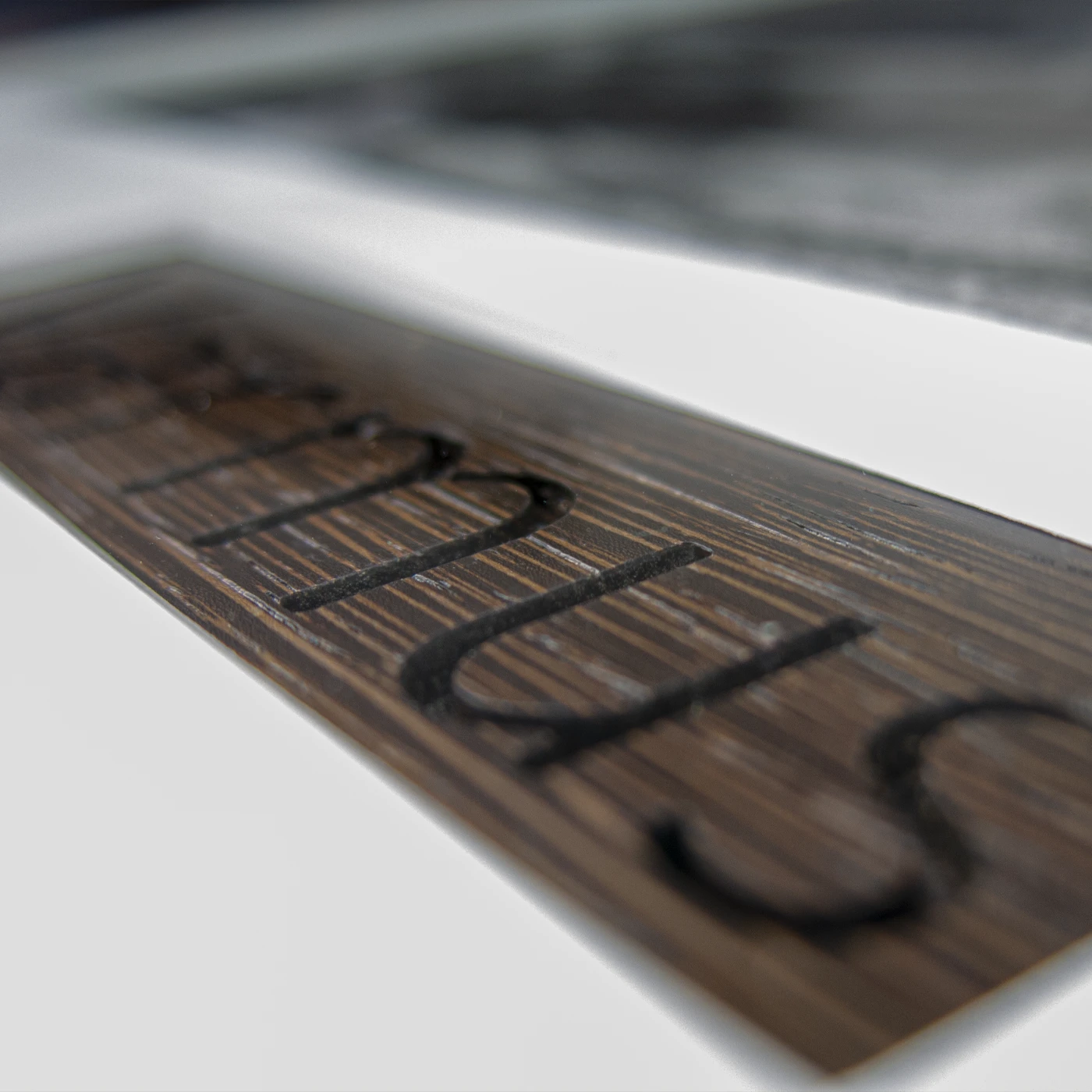 close-up of wood engraving on dark brown Wenge wood
