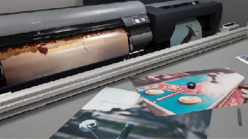 Close-up of a professional 60" Canon inkjet printer with a print half out of the machine and other prints on a desk