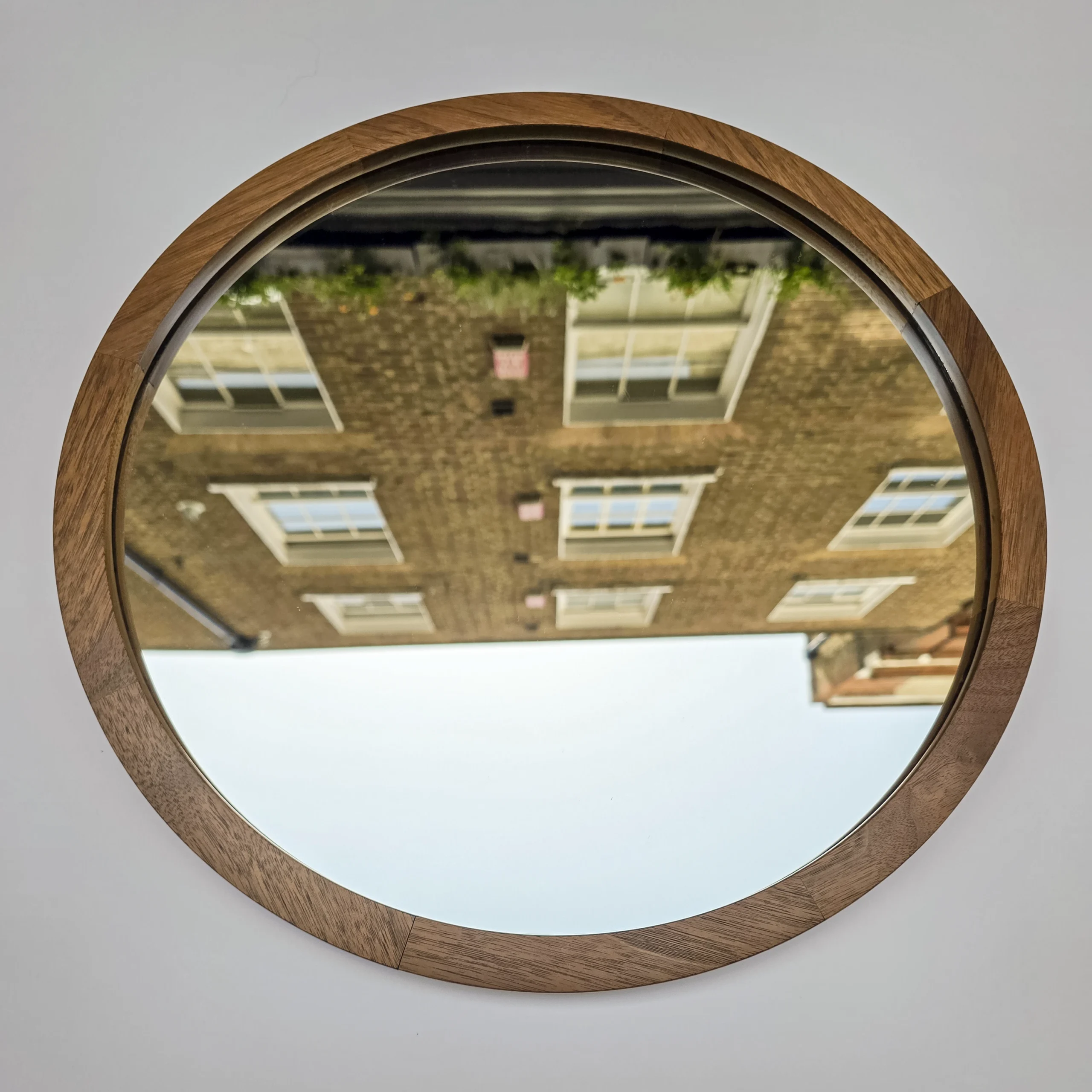 a round mirror in a walnut frame