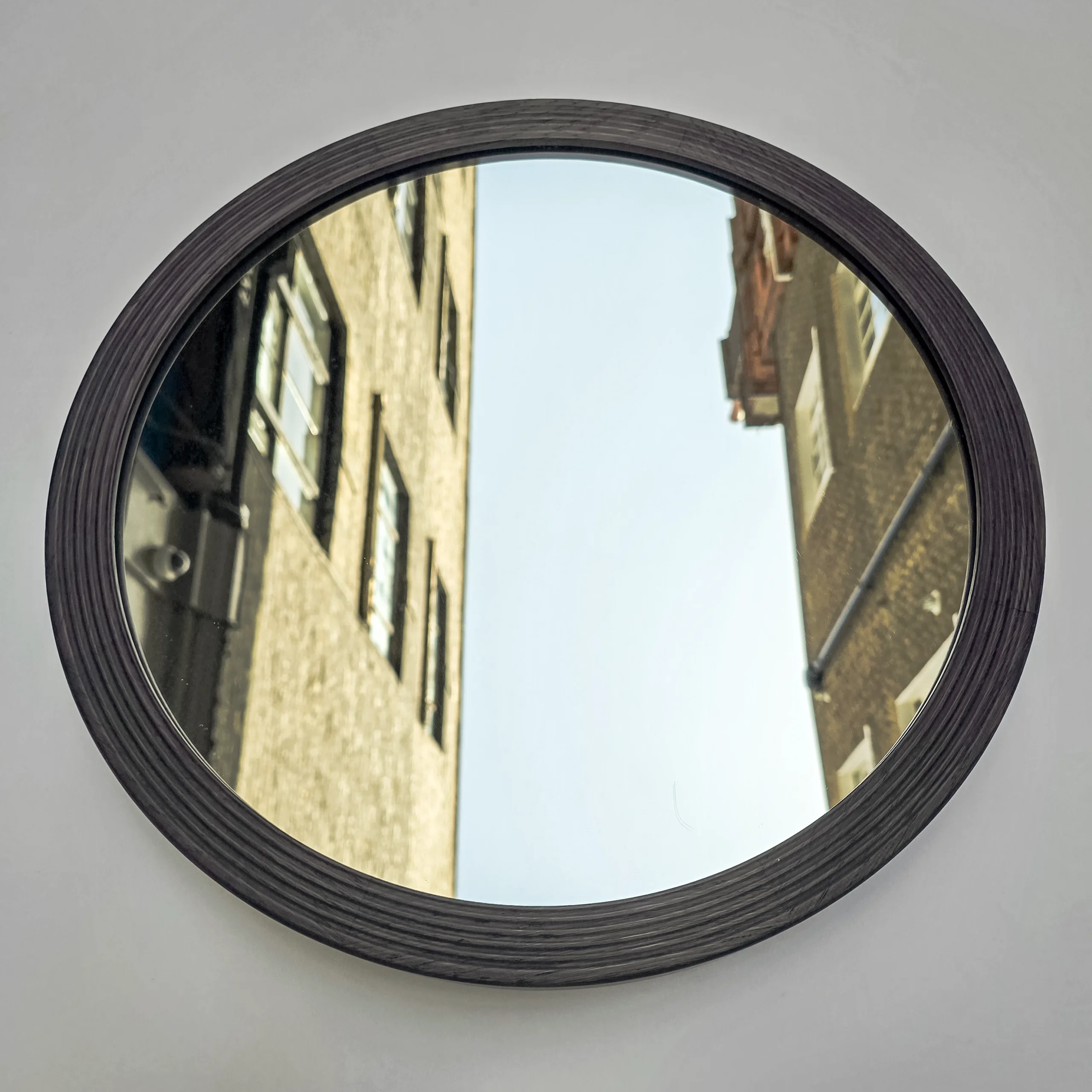 a round mirror in a black ribbed frame