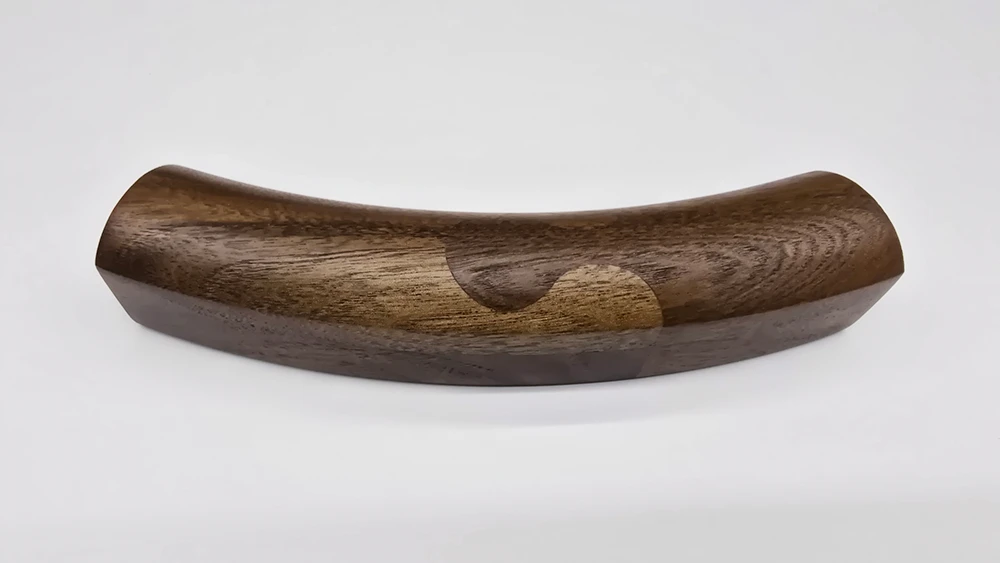 Curved walnut picture frame section with a puzzle joint on a white background