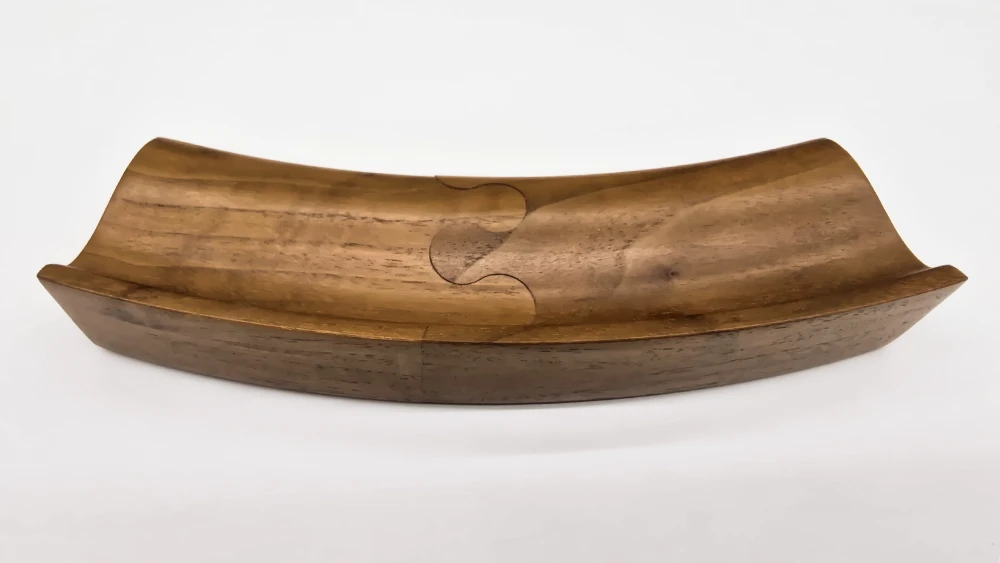 Curved picture frame section in light walnut with a double-puzzle joint on a white background