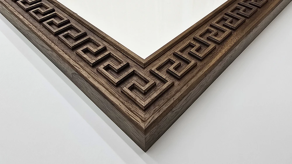 close up of a geometric Greek carving around the rim of a walnut picture frame