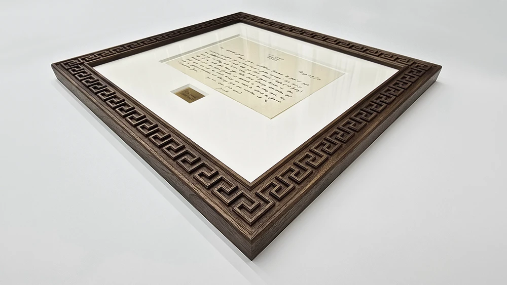 custom carved picture frame on a soft grey background. Made from walnut and showing a geometric carved design all round.
