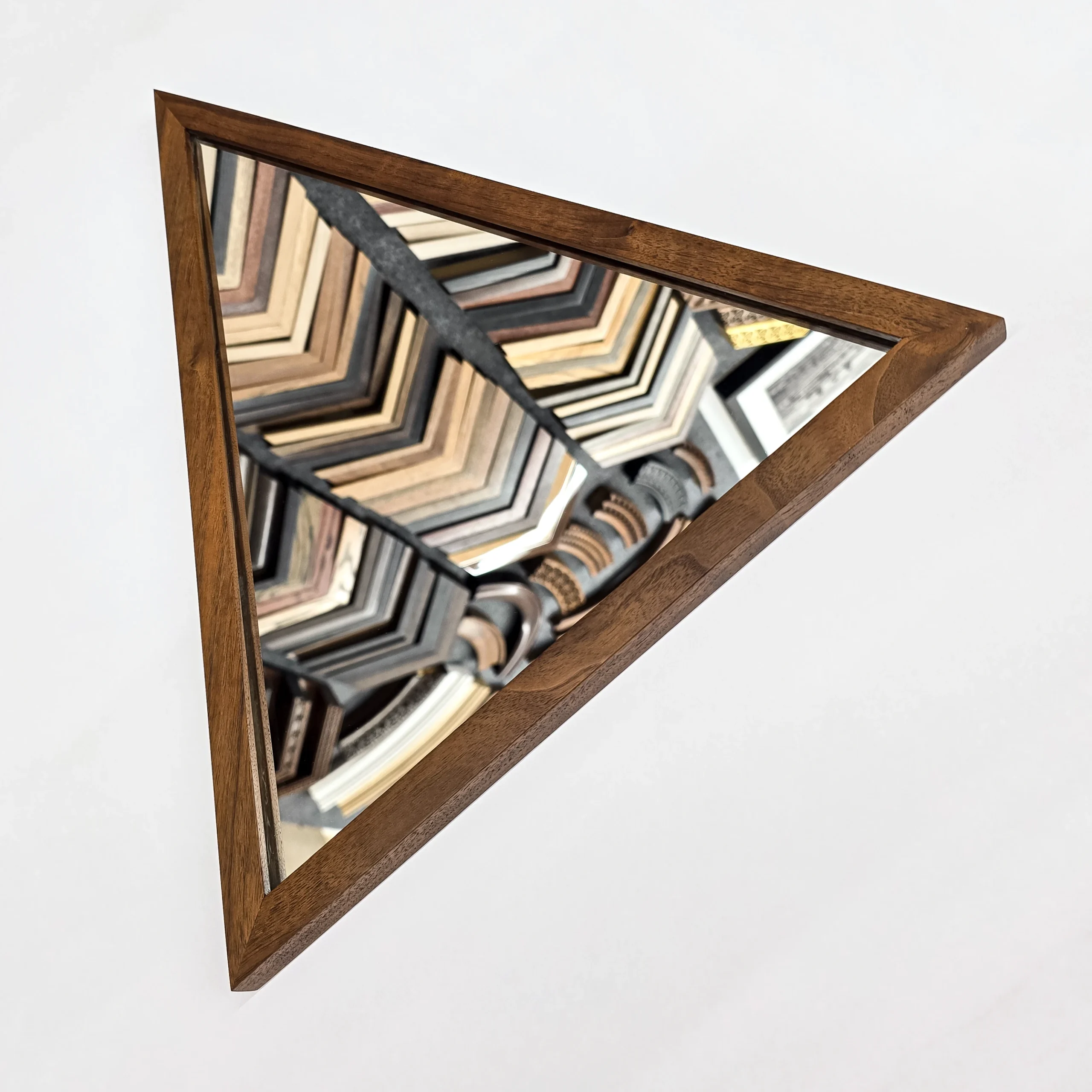 a triangular mirror and frame made from walnut