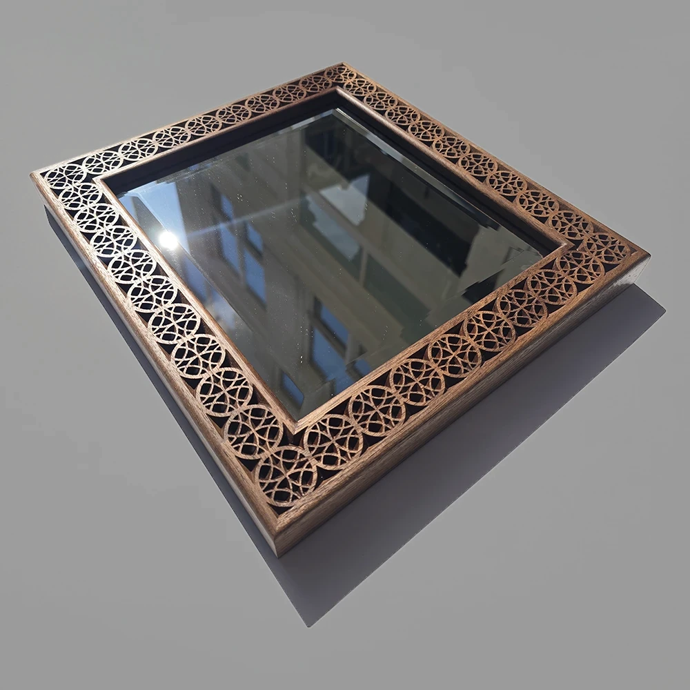 A bevel edged mirror in a custom carved walnut frame with an Islamic art inspired pattern.