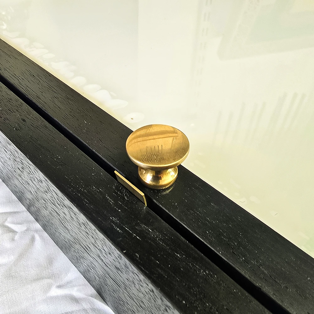 close-up of 1930s 15mm wide brass doorknob on a black walnut cabinet frame